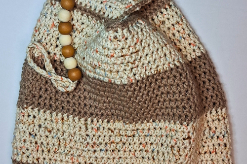 Close-up of a medium crochet Japanese knot bag in beige and spunky sand striped 100% cotton with natural wood round beads and keychain loop embellishment