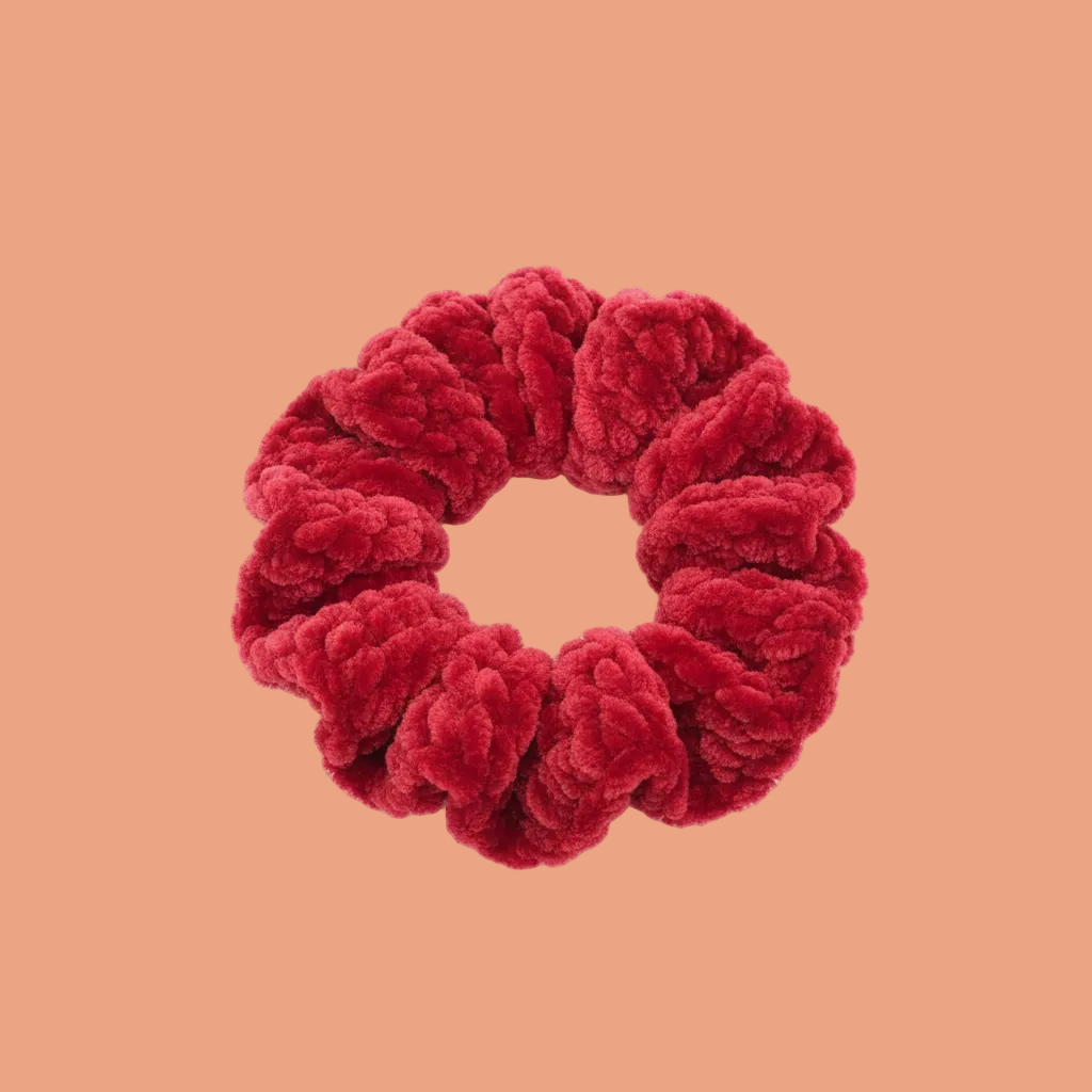 Vibrant cherry red velvet scrunchie on white background